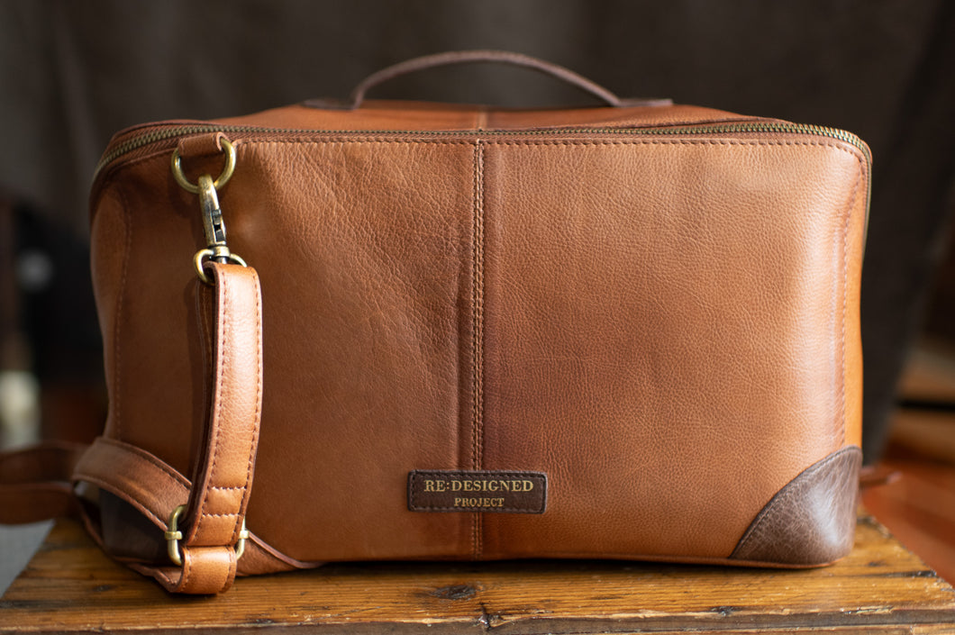 Brown leather bag with a visible brand label on a wooden surface