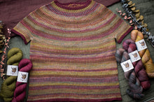 Load image into Gallery viewer, Knitted sweater with colorful yarn skeins on a textured surface