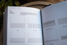 Load image into Gallery viewer, Open book with technical drawings and text on a wooden surface