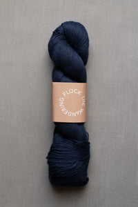 Navy skein of yarn with a label on a gray background