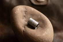 Load image into Gallery viewer, Silver decorative object on a textured brown surface