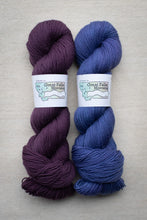 Load image into Gallery viewer, Two skeins of yarn, one purple and one blue, with &#39;Great Falls Montana&#39; labels on a beige background.