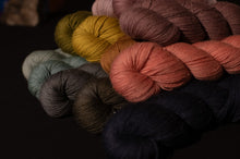 Load image into Gallery viewer, Assorted skeins of yarn in various colors on a dark background
