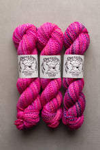 Load image into Gallery viewer, Three skeins of vibrant pink and magenta variegated yarn with white paper labels reading 'Dream Spinner Spincycle Yarns' on a neutral gray background.