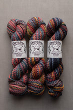 Load image into Gallery viewer, Three skeins of DreamSpark Spincycle Yarns in a variegated multicolor blend of red, blue, green, yellow, and orange, arranged side-by-side on a neutral gray background.