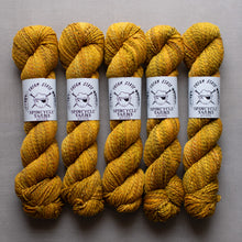 Load image into Gallery viewer, Five skeins of yellow yarn with Spincycle Yarns labels on a gray background