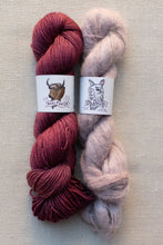 Load image into Gallery viewer, Two skeins of yarn laid side by side on a neutral textured background. The left skein is a rich burgundy/maroon, and the right skein is a pale blush pink.