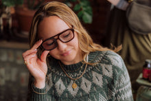 Load image into Gallery viewer, Woman adjusting glasses with a blurred indoor background