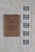 Load image into Gallery viewer, Set of 'Wild Wild Brunette' labels on a marble surface with packaging.
