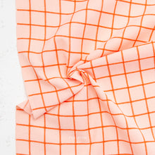 Load image into Gallery viewer, Pink fabric with orange grid pattern on a white background