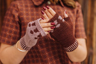 Person wearing brown and pink patterned fingerless gloves with a blurred background