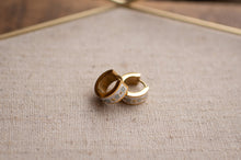 Load image into Gallery viewer, Gold rings with intricate designs on a textured fabric surface