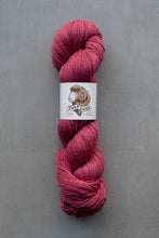 Load image into Gallery viewer, Pink skein of yarn with a label on a gray background