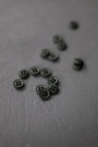 Small black buttons scattered on a gray surface