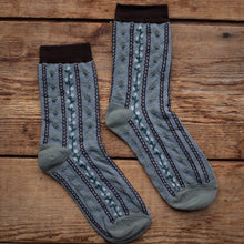 Load image into Gallery viewer, Pair of patterned socks on a wooden surface