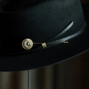 Black hat with a decorative band featuring a gold buckle and turquoise stone.