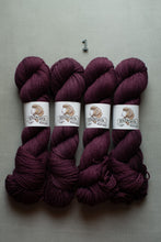 Load image into Gallery viewer, Four skeins of yarn in a deep burgundy-purple color, arranged side by side on a light gray background. Each skein has a white paper label with the brand name 'Homick' and a small metal number '1' placed above them.