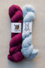 Load image into Gallery viewer, Two skeins of yarn on a neutral beige background. The left skein is a rich magenta-purple with a white paper label featuring a bison illustration and the text 'Boise Powder'.