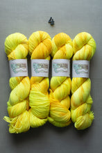Load image into Gallery viewer, Four skeins of yellow yarn with visible brand labels on a gray background