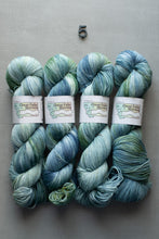 Load image into Gallery viewer, Four skeins of blue and green yarn with labels on a gray background