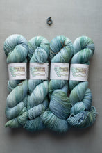 Load image into Gallery viewer, Four skeins of green and blue yarn with labels on a gray background