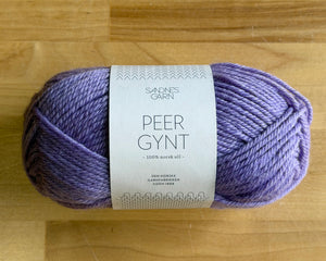 Purple yarn ball with a label on a wooden surface