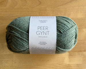 Ball of green yarn with a label on a wooden surface