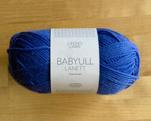 Load image into Gallery viewer, Blue skein of yarn with a label on a wooden surface
