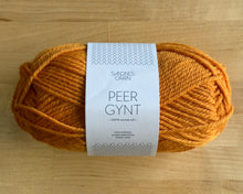Load image into Gallery viewer, Ball of orange yarn with a label on a wooden surface