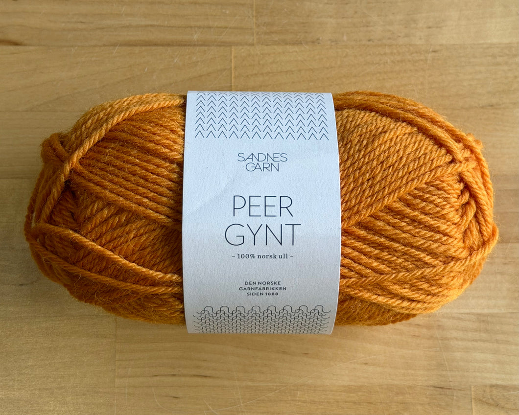 Ball of orange yarn with a label on a wooden surface