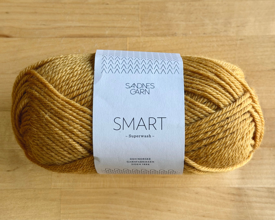 Ball of yellow yarn with a label on a wooden surface