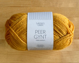 Yellow yarn skein with a label on a wooden surface