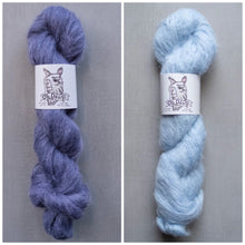 Load image into Gallery viewer, Two skeins of yarn, one purple and one blue, with labels on a gray background.