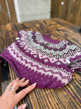 Load image into Gallery viewer, Knitted purple and white patterned item on a wooden surface with a hand touching it.