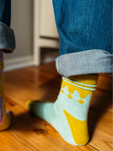 Load image into Gallery viewer, Close-up of feet wearing colorful socks on a wooden floor.