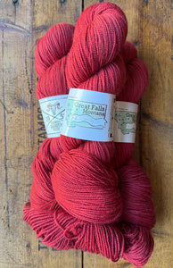 Red yarn skeins with 'Great Falls Montana' label on a wooden surface