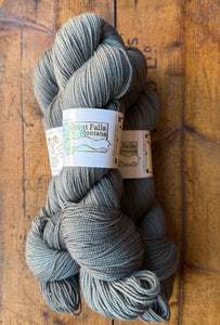 Gray skein of yarn with labels on a wooden surface