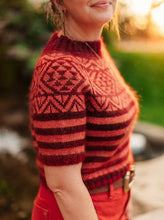 Load image into Gallery viewer, Person wearing a red and black patterned sweater outdoors with a blurred natural background