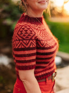 Person wearing a red and black patterned sweater outdoors with a blurred natural background