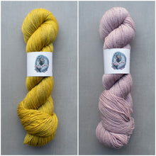 Load image into Gallery viewer, Two skeins of yarn, one yellow and one pink, on a gray background with labels.