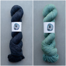 Load image into Gallery viewer, Two skeins of yarn, one dark blue and one teal, on a gray background with a brand label.