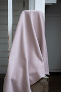 Pink towel draped over a wooden surface with a white wall in the background