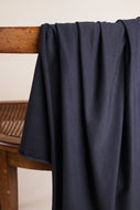Navy blue fabric draped over a wooden chair against a beige wall.