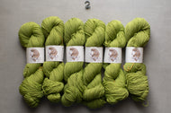 Green yarn skeins with labels on a gray background