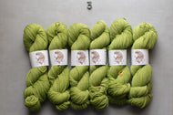 Green yarn skeins with labels on a gray background