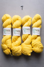 Load image into Gallery viewer, Four skeins of yellow yarn with labels on a gray background