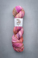 Load image into Gallery viewer, Multicolored skein of yarn with a label on a gray background