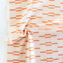 Load image into Gallery viewer, Fabric with orange and white geometric pattern on a textured surface