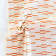 Fabric with orange and white geometric pattern on a textured surface