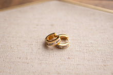 Load image into Gallery viewer, Gold hoop earrings on a textured beige surface